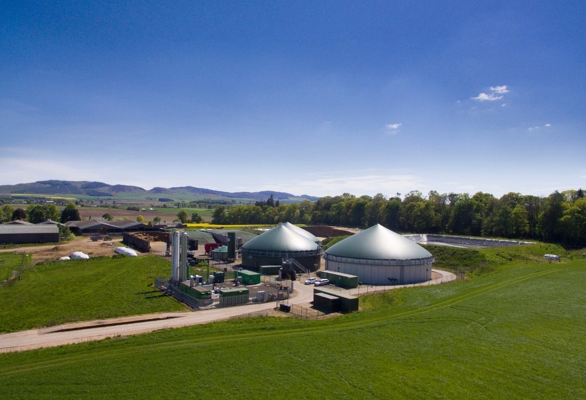 Biogas plant with green digester domes under a blue sky